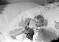 Városi ruhás kislány az ifjú párnak elkészített ágyon