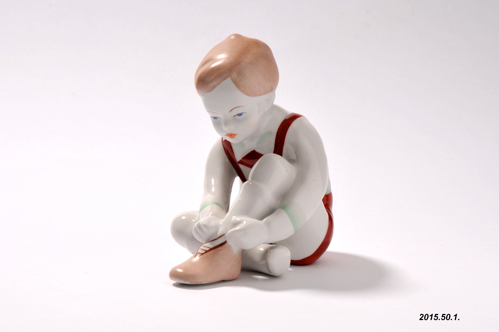 Porcelán dísztárgy, cipőfűzőt kötő kisfiú, Aquincum Porcelángyár terméke (Óbudai Múzeum CC BY-NC-SA)