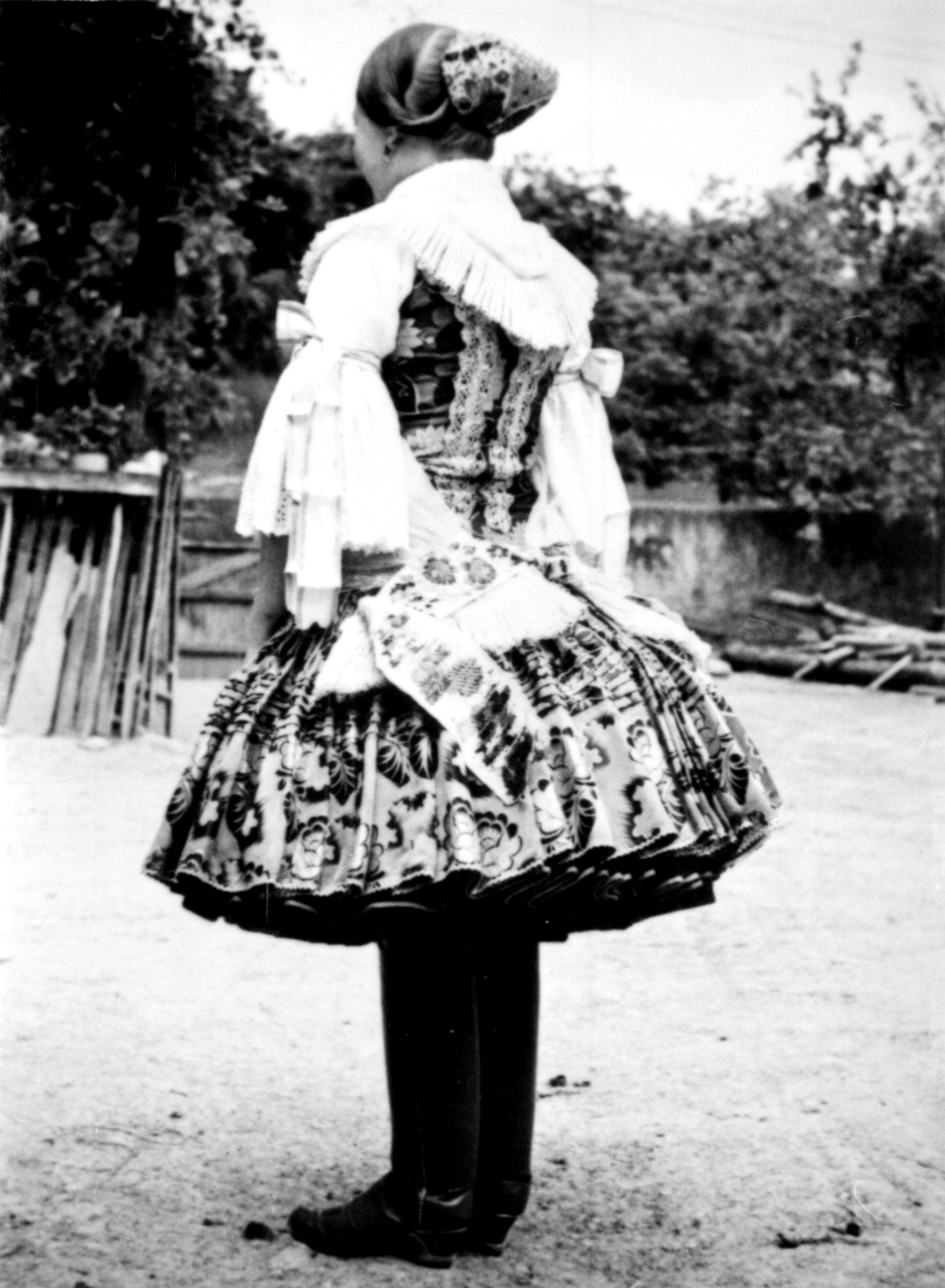 Lány ünnepi viseletben féketővel (MTA BTK Néprajztudományi Intézet CC BY-NC-SA)